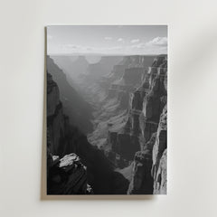 Grand Canyon Shadows Poster by Bozetto: Svartvitt foto med karga klippor och en skuggig dal under en delvis molnig himmel, tryckt på FSC-certifierat premiumpapper med elegant matt yta. Perfekt som Grand Canyon väggkonst.