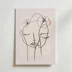 Bozetto Floral Line Faces Poster har minimalistisk svart linjekonst av två ansikten med slutna ögon och delikata blomsterskisser på en ljus beige matt yta, vilket skapar en lugn och intim atmosfär.