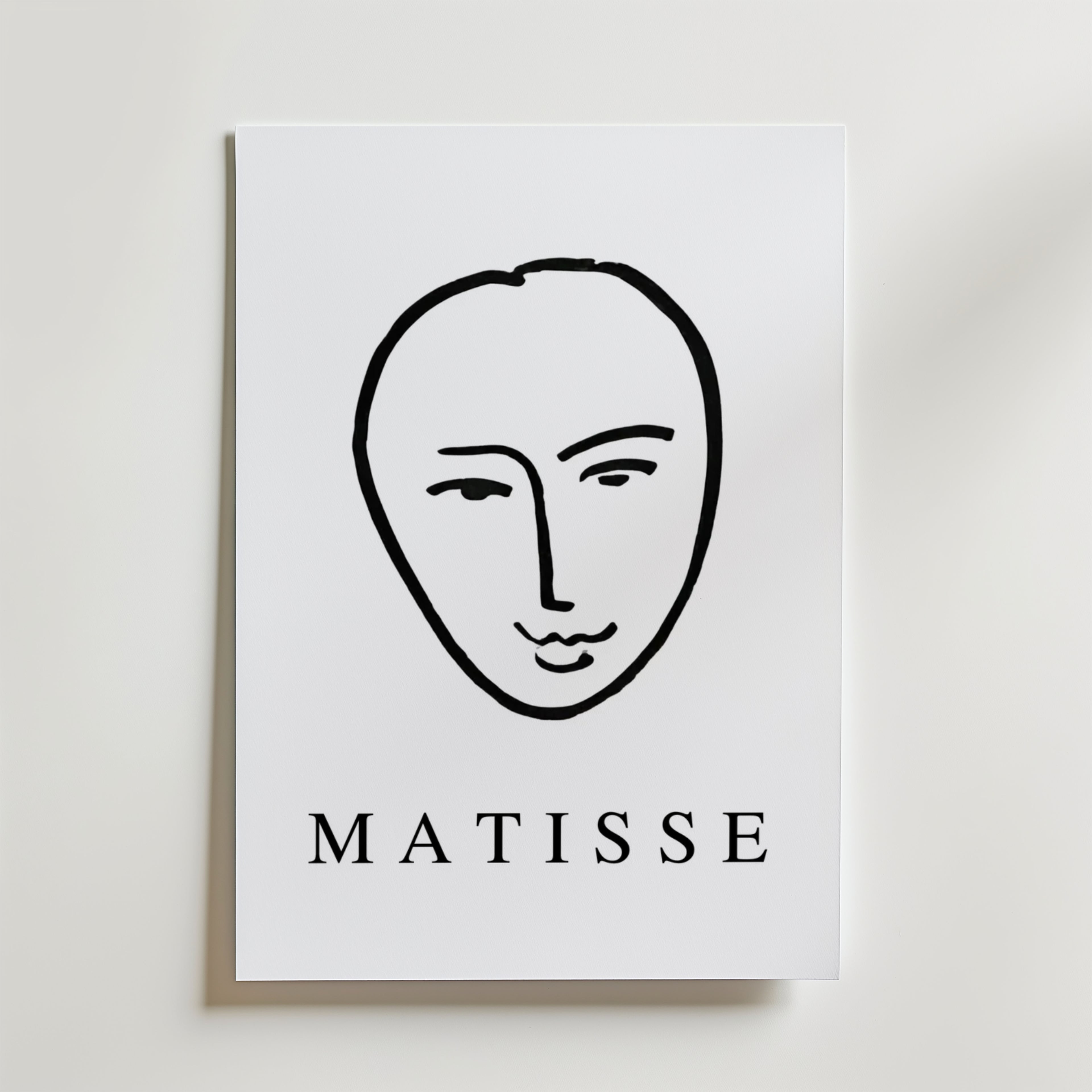 Minimal Matisse Poster by Bozetto har ett minimalistiskt svart linjeansikte på en vit bakgrund med fet "MATISSE" text, tryckt på premiumpapper med en matt finish för en elegant look.