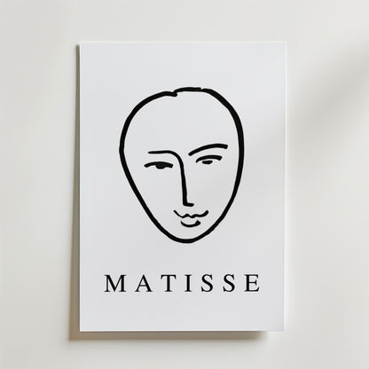 Minimal Matisse Poster by Bozetto har ett minimalistiskt svart linjeansikte på en vit bakgrund med fet "MATISSE" text, tryckt på premiumpapper med en matt finish för en elegant look.