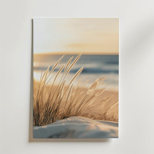 Meadow Beach Feeling Poster by Bozetto visar strandgräs i sanden med mjukt ljus och ett suddigt hav, placerad på en vit vägg. Dess lyxigt matta yta ger ett raffinerat och elegant uttryck.