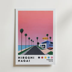 Bozetto Hiroshi Nagai Sunset Coast Poster föreställer en rosa solnedgång över en palmkantad kustväg som leder till en akvariebyggnad, med "Hiroshi Nagai Tokyo 1973" och färgade prickar längst ner.