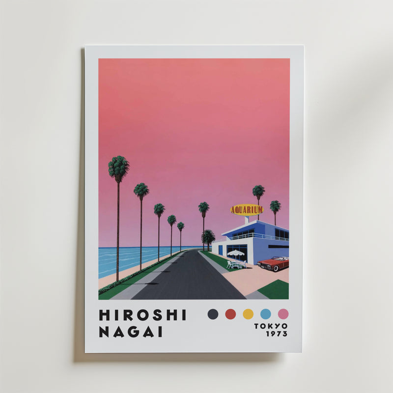 Bozetto Hiroshi Nagai Sunset Coast Poster föreställer en rosa solnedgång över en palmkantad kustväg som leder till en akvariebyggnad, med "Hiroshi Nagai Tokyo 1973" och färgade prickar längst ner.