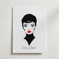 Den tidlösa Audrey Hepburn Postern från Bozetto har en minimalistisk svartvit design av Audrey med kort hår, djärv eyeliner och röda läppar på matt papper. "Audrey Hepburn" är elegant skrivet under och skapar en klassisk, tidlös look.