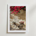 Postern Bougainvillea Bicycle Poster från Bozetto, tryckt på FSC-certifierat premiumpapper, visar en vintagecykel med blomkorgar mot en solbelyst vägg och en livfull rosa bougainvillea ovanför för en högkvalitativ finish.