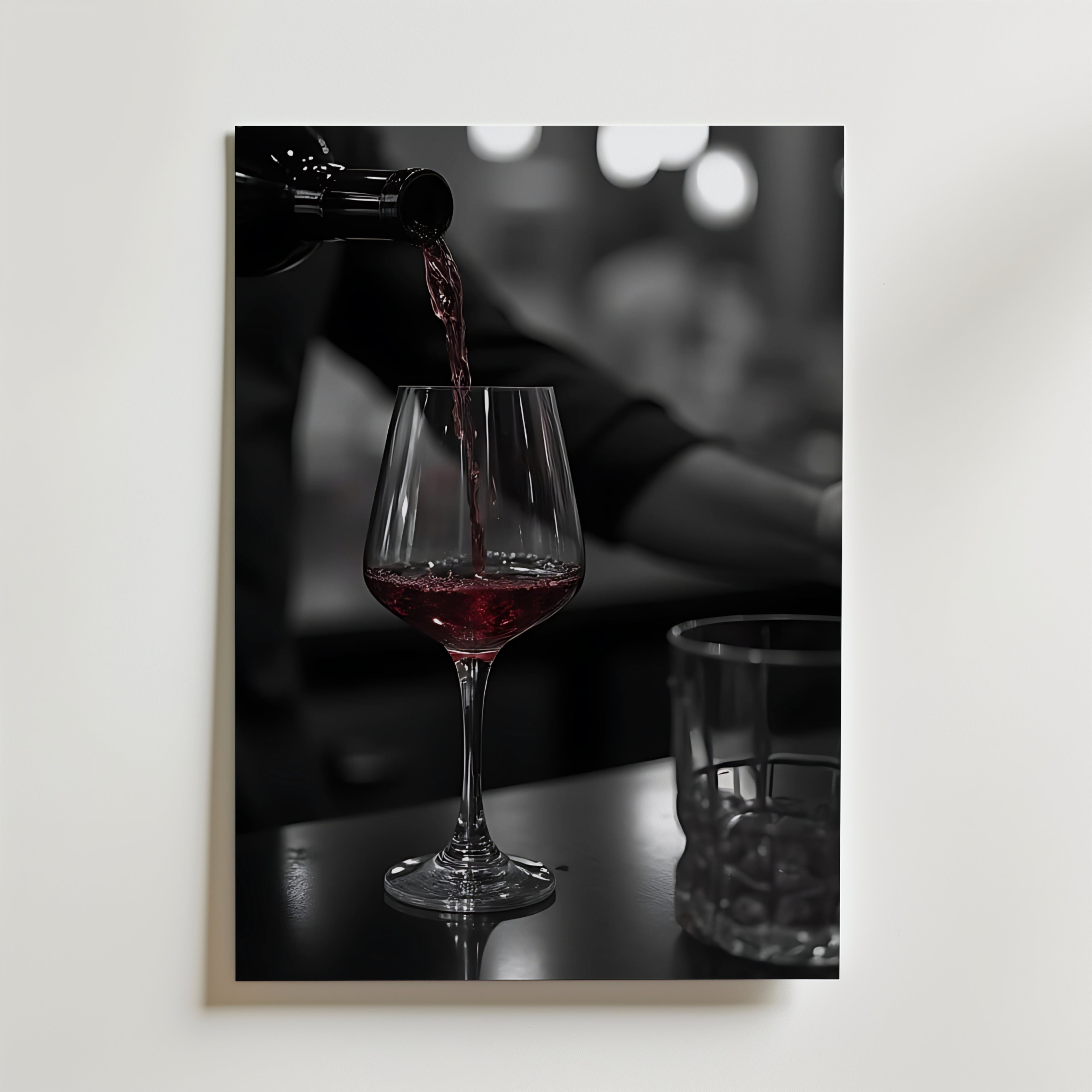 Bozetto Pouring Passion Wine Poster visar rött vin som hälls upp i ett glas på en mörk yta bredvid ett tomt glas, med mjukt suddiga bokeh-ljus som förstärker skönheten i vin i rörelse.