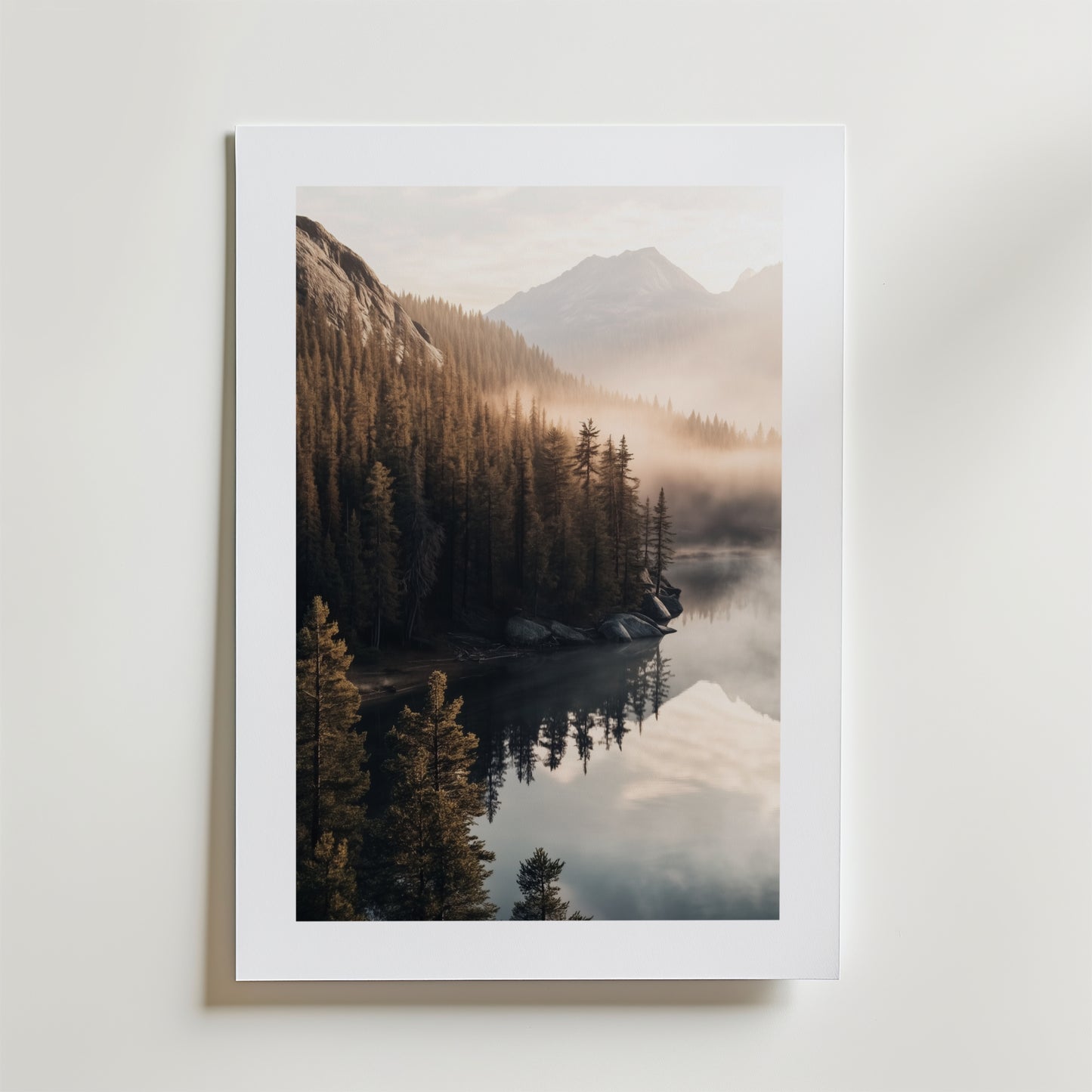 Bozetto "Between the Misty Peaks Poster" visar ett dimmigt bergslandskap med tallar och en stilla sjö på FSC-certifierat premiumpapper, lyxigt matt yta och vit kant mot en enfärgad vit bakgrund.