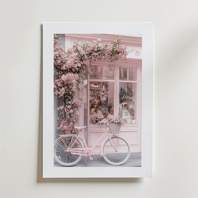 La Vie en Rose Poster by Bozetto föreställer en butikslokal i mjuka rosa toner, blommande blommor och en rosa vintage cykel, vilket skapar en romantisk pastell look med en elegant, lyxigt matt yta.