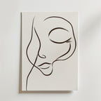 Dreamy Line Art Face Poster" av Bozetto föreställer ett lugnt ansikte med slutna ögon och böjda läppar, tecknat med minimalistiska svarta linjer på vit canvas för en elegant, abstrakt look.