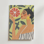 Citrus Muse Poster by Bozetto föreställer en kvinna med kort mörkt hår som håller i en grapefruktskiva, bär en randig klänning och örhängen med citronskivor bland bladgröna växter - tryckt på premiumpapper av Matt Yta.