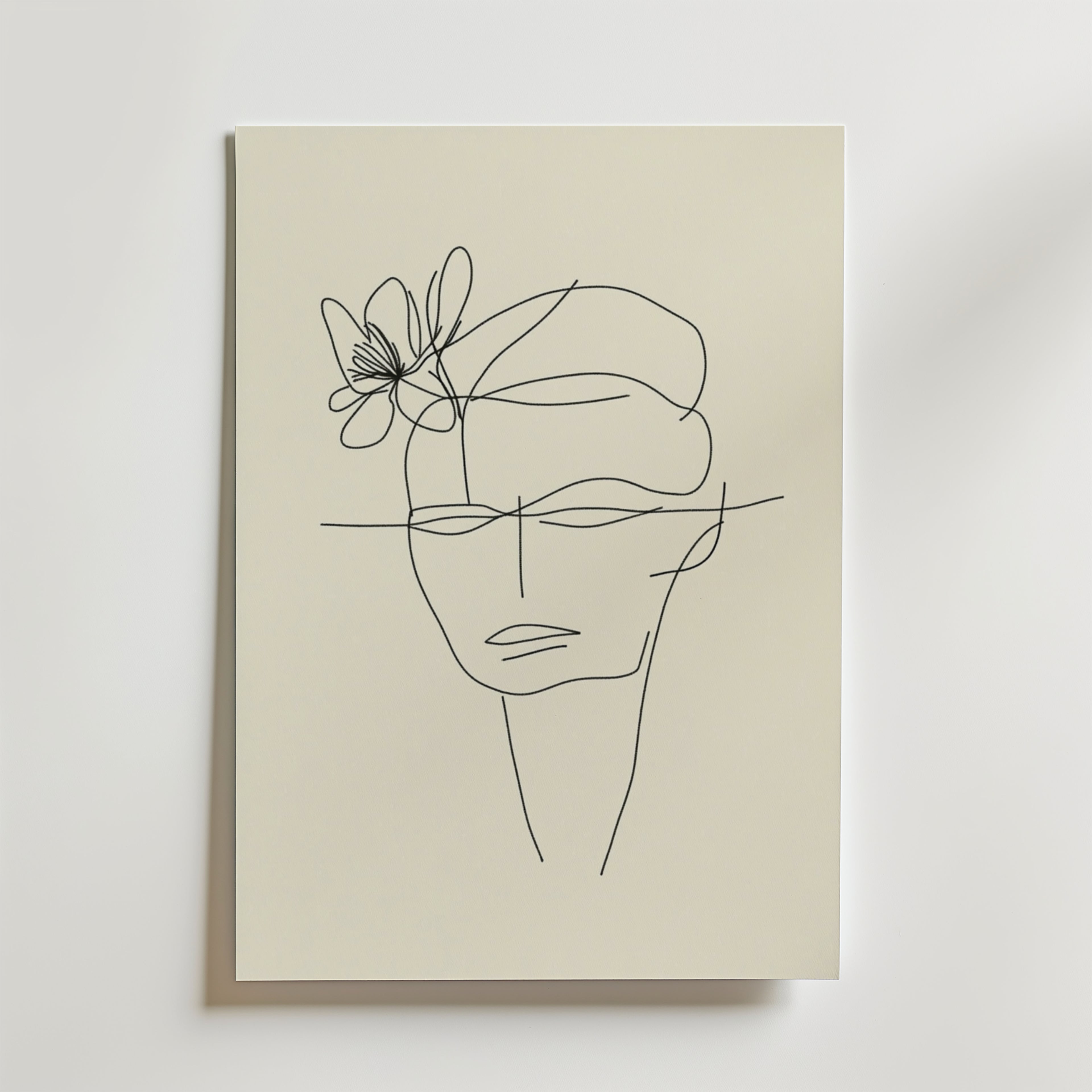 Bozetto Floral Mind Line Art Poster föreställer ett ansikte med en blomma på huvudet, tecknat med en enda svart linje på beige premiumpapper. Detta FSC-certifierade konstverk visas monterat på en vit vägg.