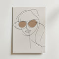 Minimalistisk linjeteckning av en kvinna med runda solglasögon, accentuerad med brun linsskuggning på en ljus bakgrund. Stylish Sunglasses Line Woman Poster från Bozetto är en perfekt modern inredningsdetalj för alla rum.
