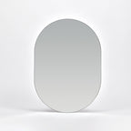 Bozetto Spegel Ark 50x70 cm, en stor ramlös väggspegel med en platt bas, är monterad på en vit vägg och reflekterar en mjuk neutral gradient.