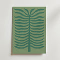 Quiet Palm Poster från Bozetto föreställer en minimalistisk stiliserad ormbunke med mörkgröna symmetriska grenar på en dovt grön bakgrund, inramad och placerad mot en ljus vägg.