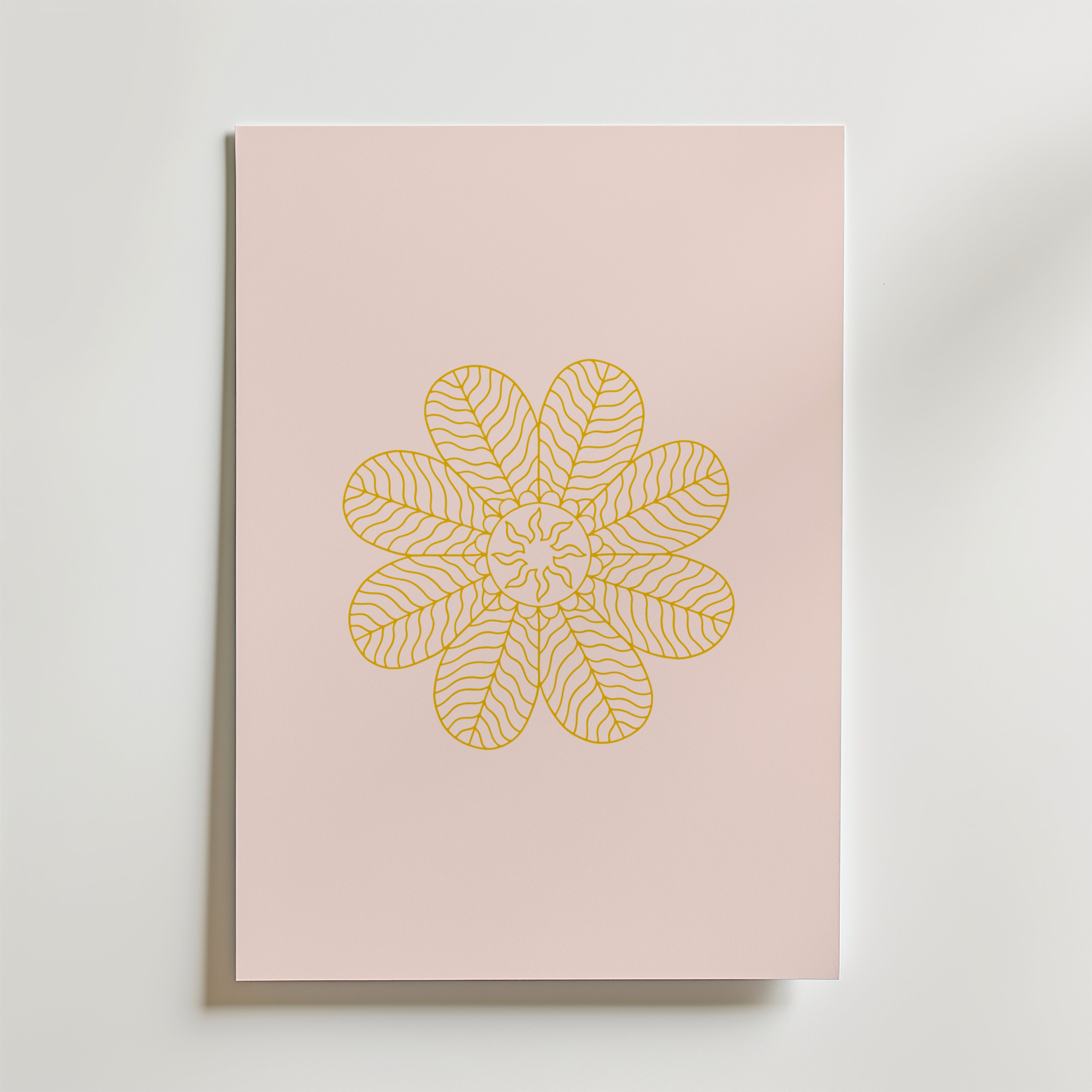 Golden Bloom on Blush Poster by Bozetto är en minimalistisk konstprint med ett guldgult, blomliknande mönster av detaljerade bladliknande kronblad på ljusrosa, som visas på en ljus yta.