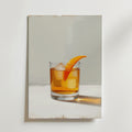 Bozetto Whiskey Orange Garnish Poster föreställer ett glas whiskey med is och en apelsintwist på en vit yta med en mjuk skugga mot en ljusgrå bakgrund, tryckt på premiumpapper med en lyxig matt finish.