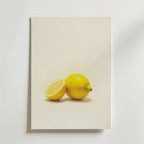 Bozetto Citrus Essence Poster visar en hel och en halv citron på en ljus bakgrund som framhäver deras ljusgula färg och naturliga textur på ett matt premiumpapper med en minimalistisk design.