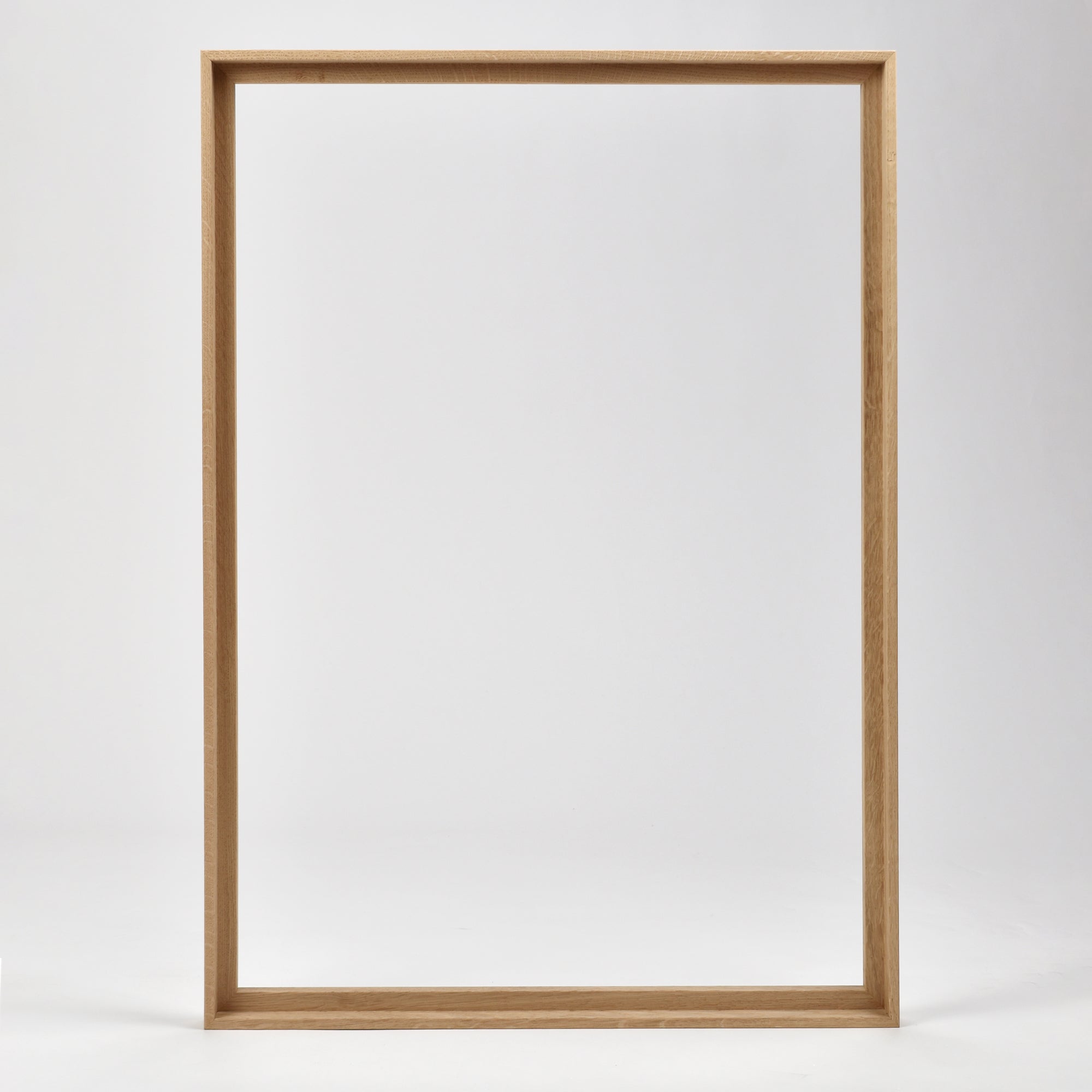 Bozetto Canvas Träram Ek är en enkel, tom tavelram i trä med en exklusiv träram, som står upprätt mot en vit bakgrund.