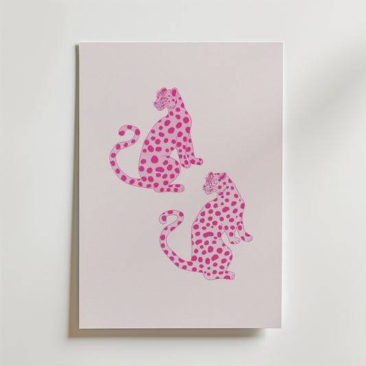 Bozetto Pink Leopard Twins Poster har ett minimalistiskt djurmotiv av två rosa leoparder med mörkare fläckar, som sitter rygg mot rygg på en pastellfärgad bakgrund - perfekt för modern inredning och visas vertikalt på en ljus yta.