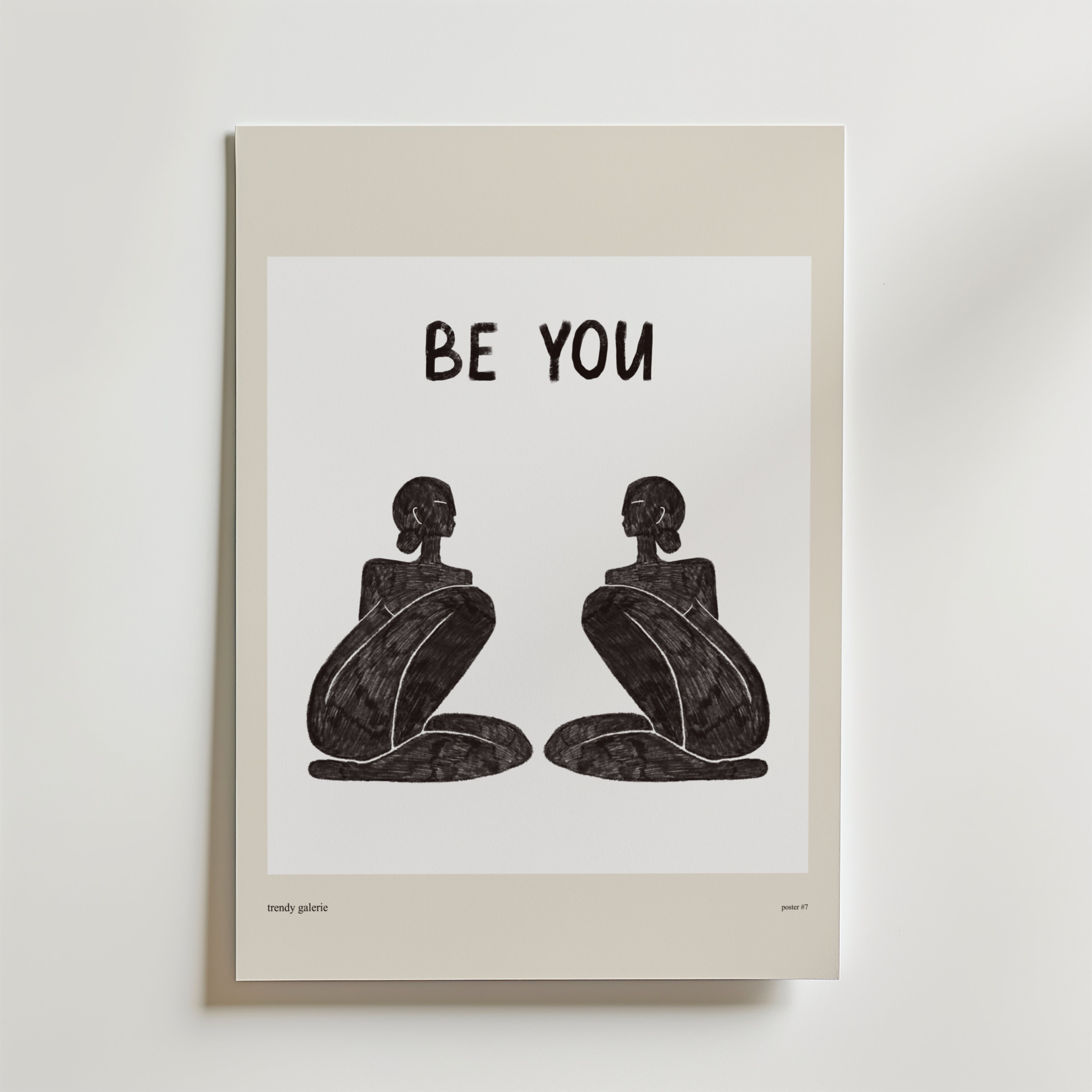 Be Your Poster från Bozetto föreställer två abstrakta, sittande svarta figurer som står vända mot varandra under en fet "BE YOU"-text som inspirerar till autenticitet på en vit bakgrund med en beige kant.